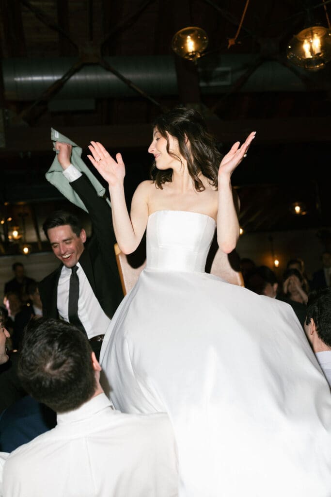 Bride and groom being lifted up on chairs dancing and having a super fun time! 
